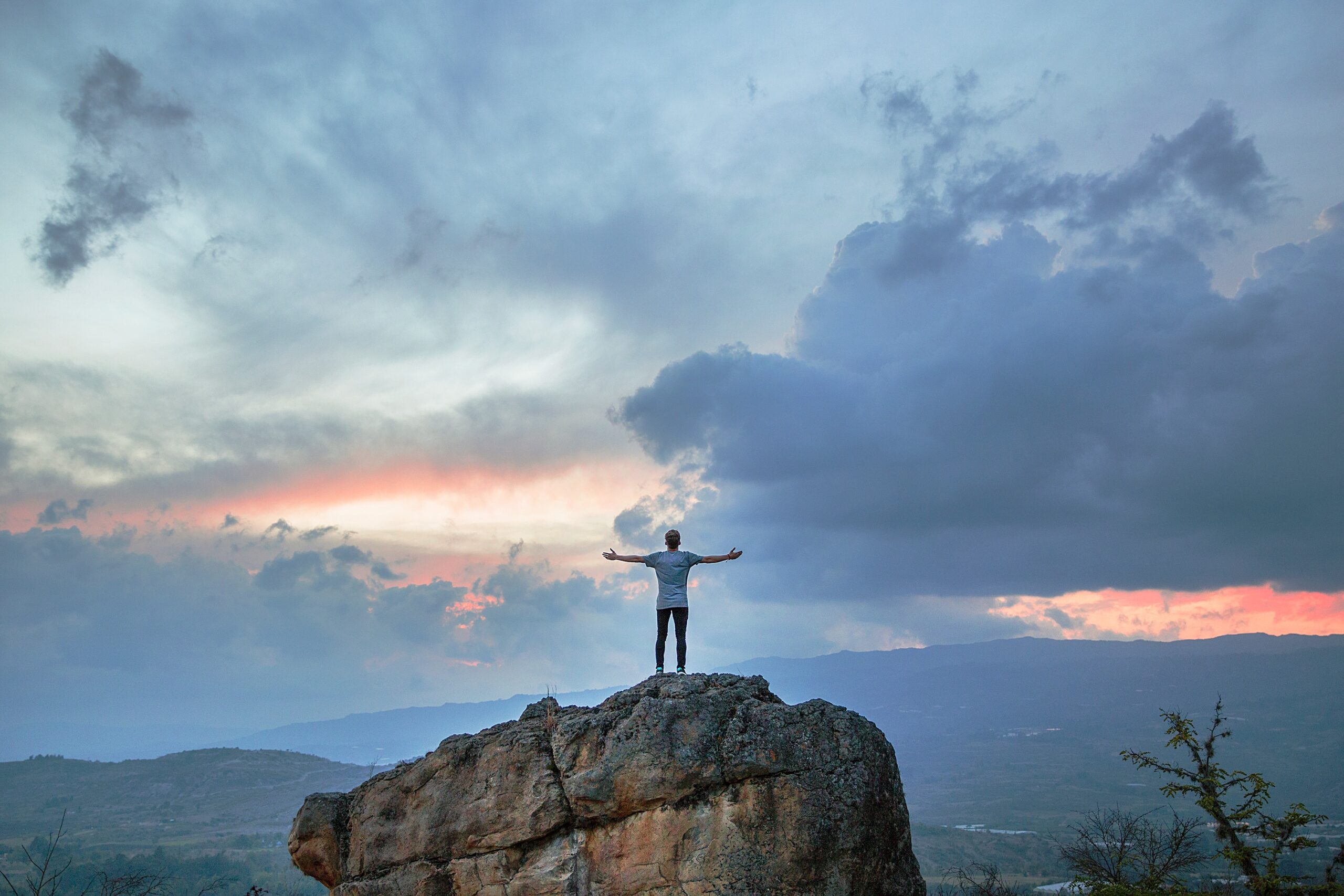 Christian with arms outstretched on top of mountain