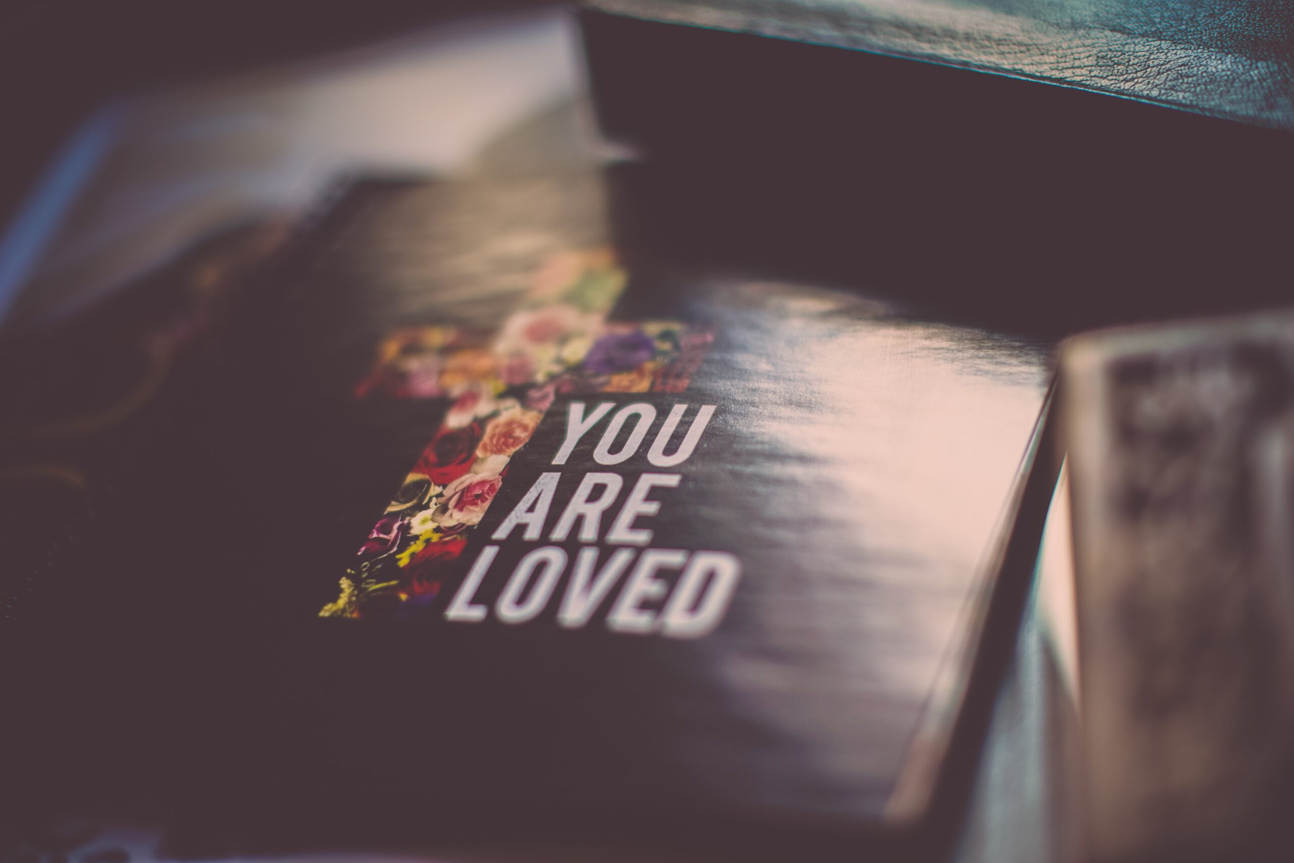 Christian with a bible that has a cross and you are loved on the cover